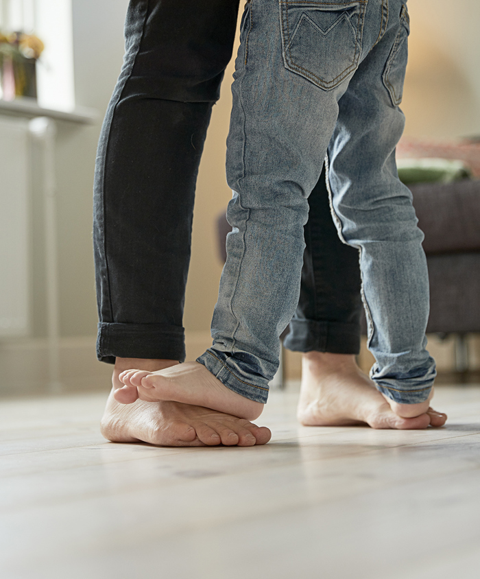 Mor og barn danser på stuegulvet med bare fødder