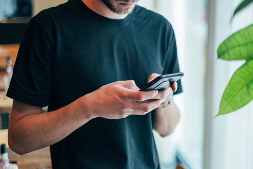 Mand taster på sin mobiltelefon.