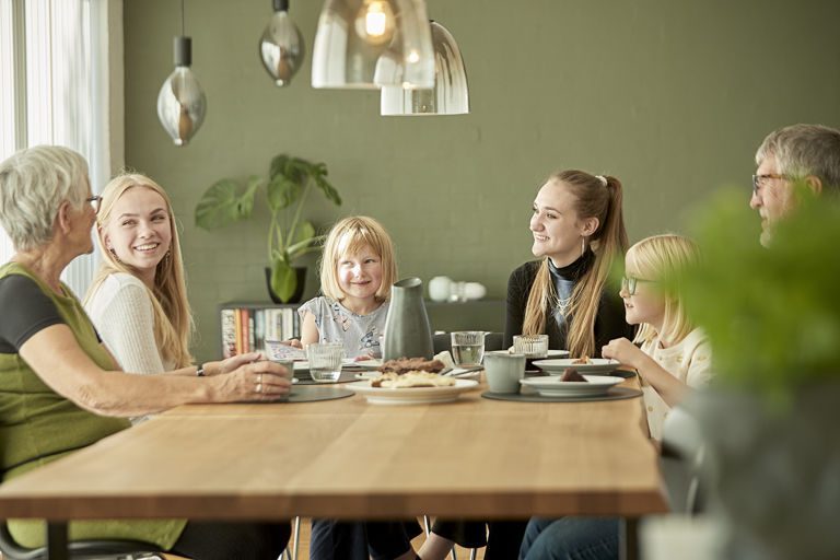 Bedsteforældre og børn hygger omkring spisebordet