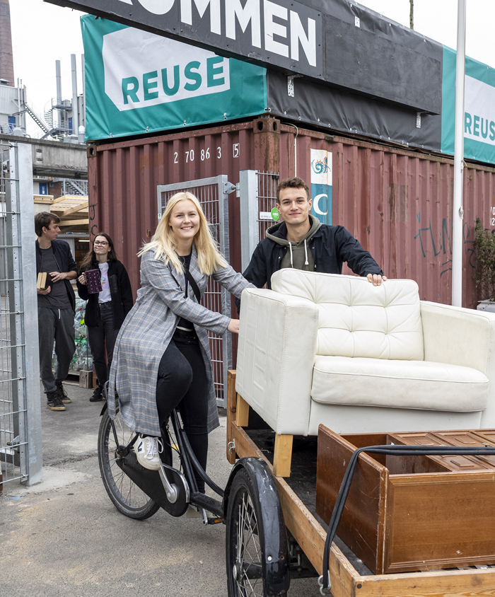 Ungt par kører på ladcykel med møbler fra REUSE