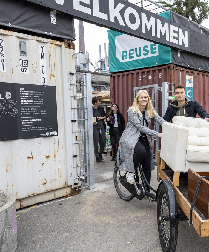Ungt par kører på ladcykel med møbler fra REUSE