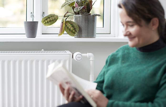 Kvinde læser foran radiator