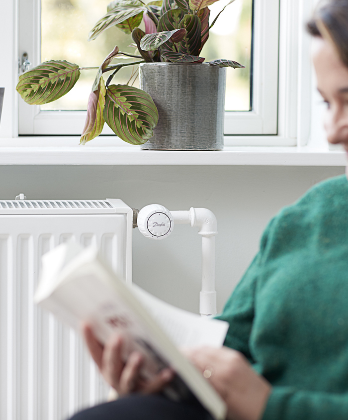 Kvinde læser foran radiator