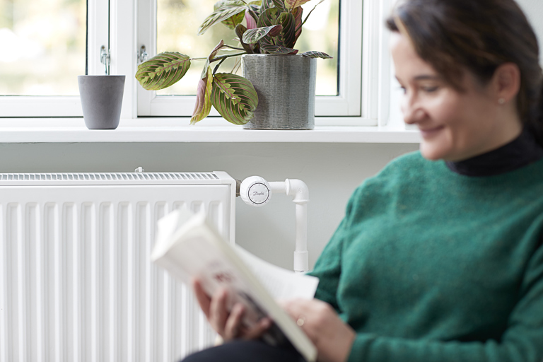 Kvinde læser foran radiator