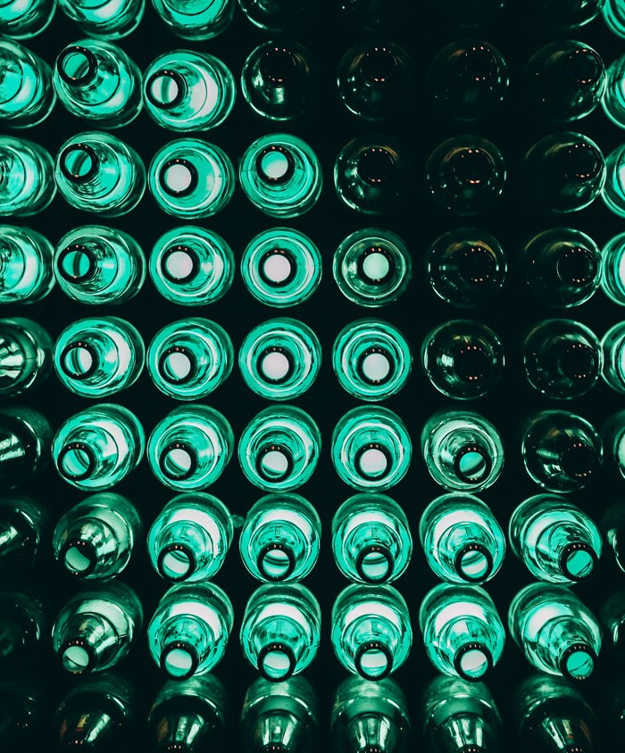 Stabel af tomme grønne glasflasker