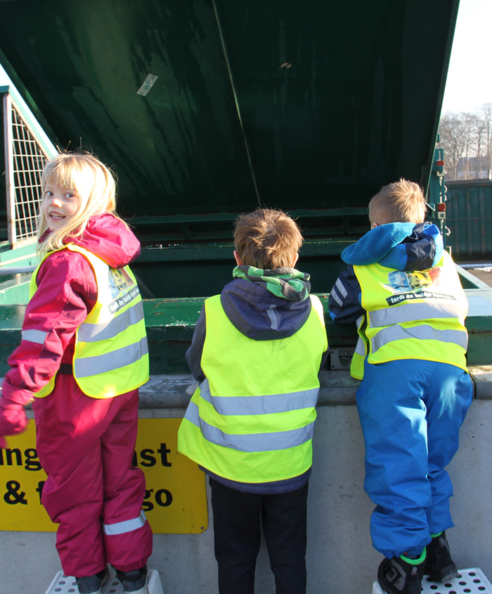 Børn undersøger papcontainer på genbrugsstation