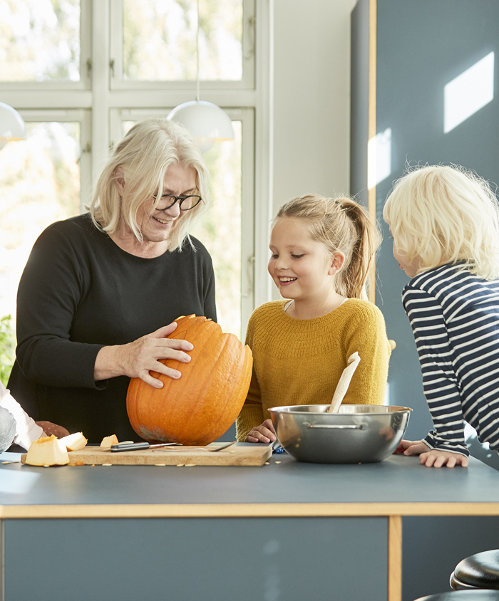 Børn og bedstemor udskærer græskar i køkkenet