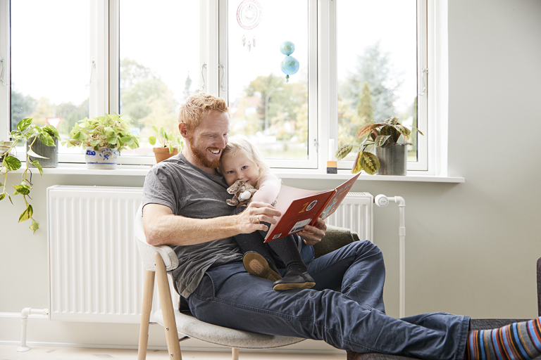 Far og datter sidder og læser foran radiator